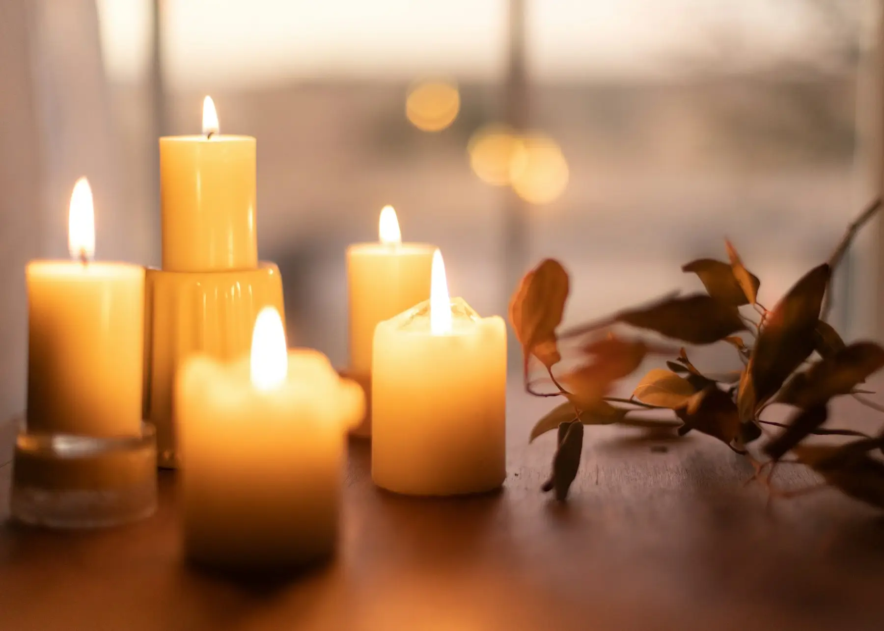 Lit white pillar candles on a wooden table
